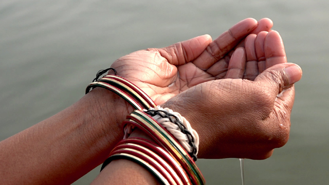 Rhunjun Kejriwal holding a palm full of water in India.